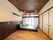 寝具のついていな介護ベッドがフローリングの部屋の中央に置かれ、壁にはエアコンが付き、大きな窓にはカーテンがなく、障子が付いている。