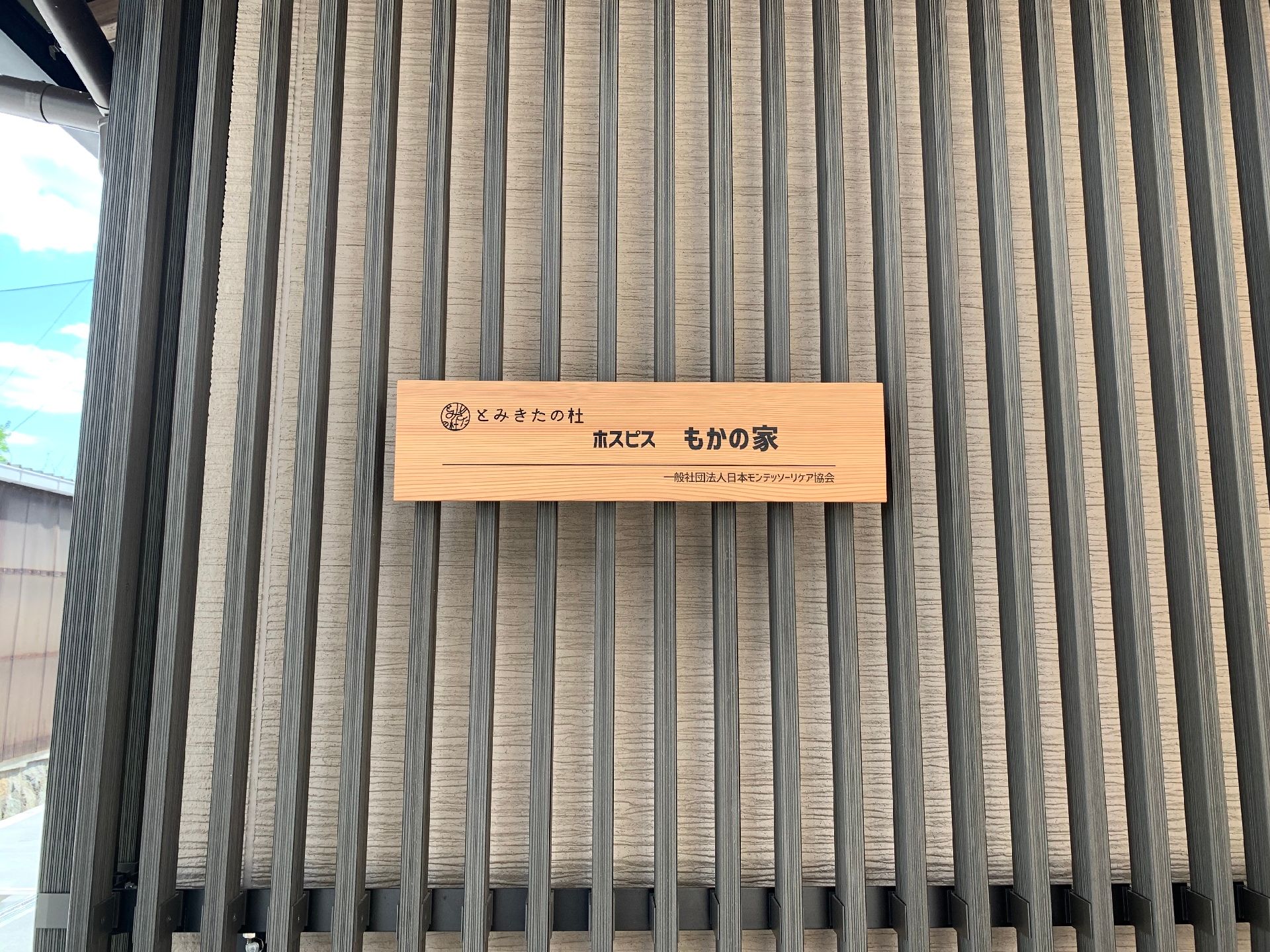 外壁には施設名が黒い文字で書かれた木製の表札が設置され、外壁にも木材が多用されている。炭焼きの木材を使用しているためモダンな雰囲気。