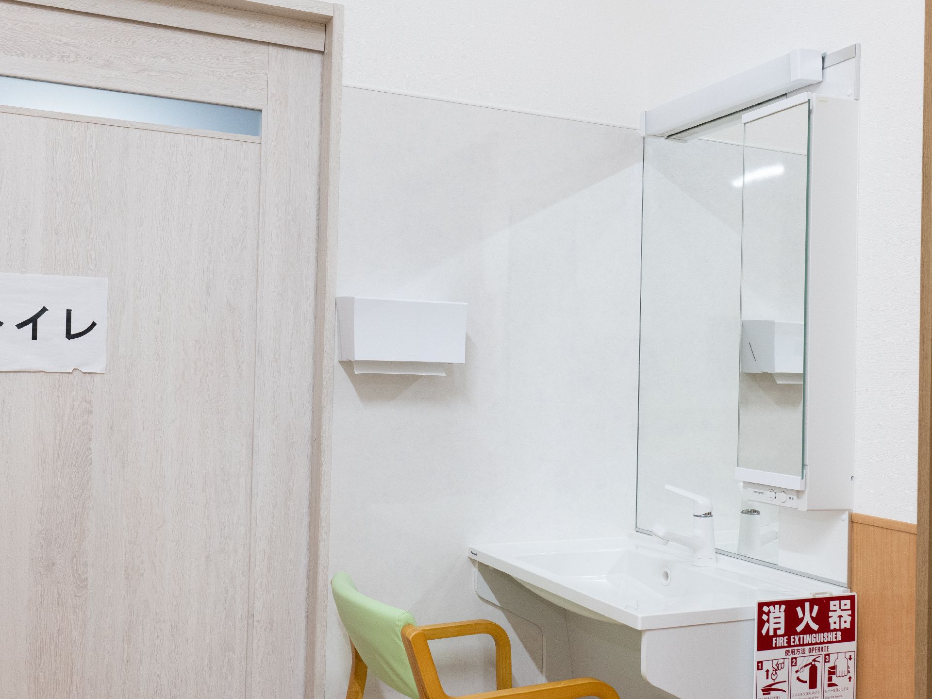 なにかを見て笑顔で手をたたいている高齢女性とスタッフの様子。施設での一場面の写真