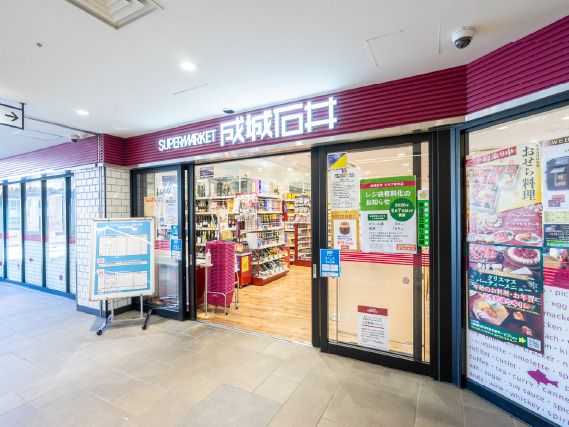 SUPERMARKET成城石井と書かれた店舗。出入り口には赤紫の買い物かごが置かれている。