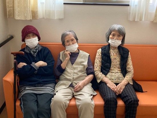 大きな窓があるフローリングの居室。寝具付きのベッド、観葉植物が置かれた白いテーブル、ソファなどがあり、ブルーと白でまとめられている。