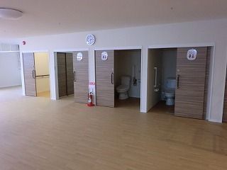 手すりが設置されたトイレが複数並んで設置されている。すべてドアはスライド式で、トイレのマークがドアに貼られている。