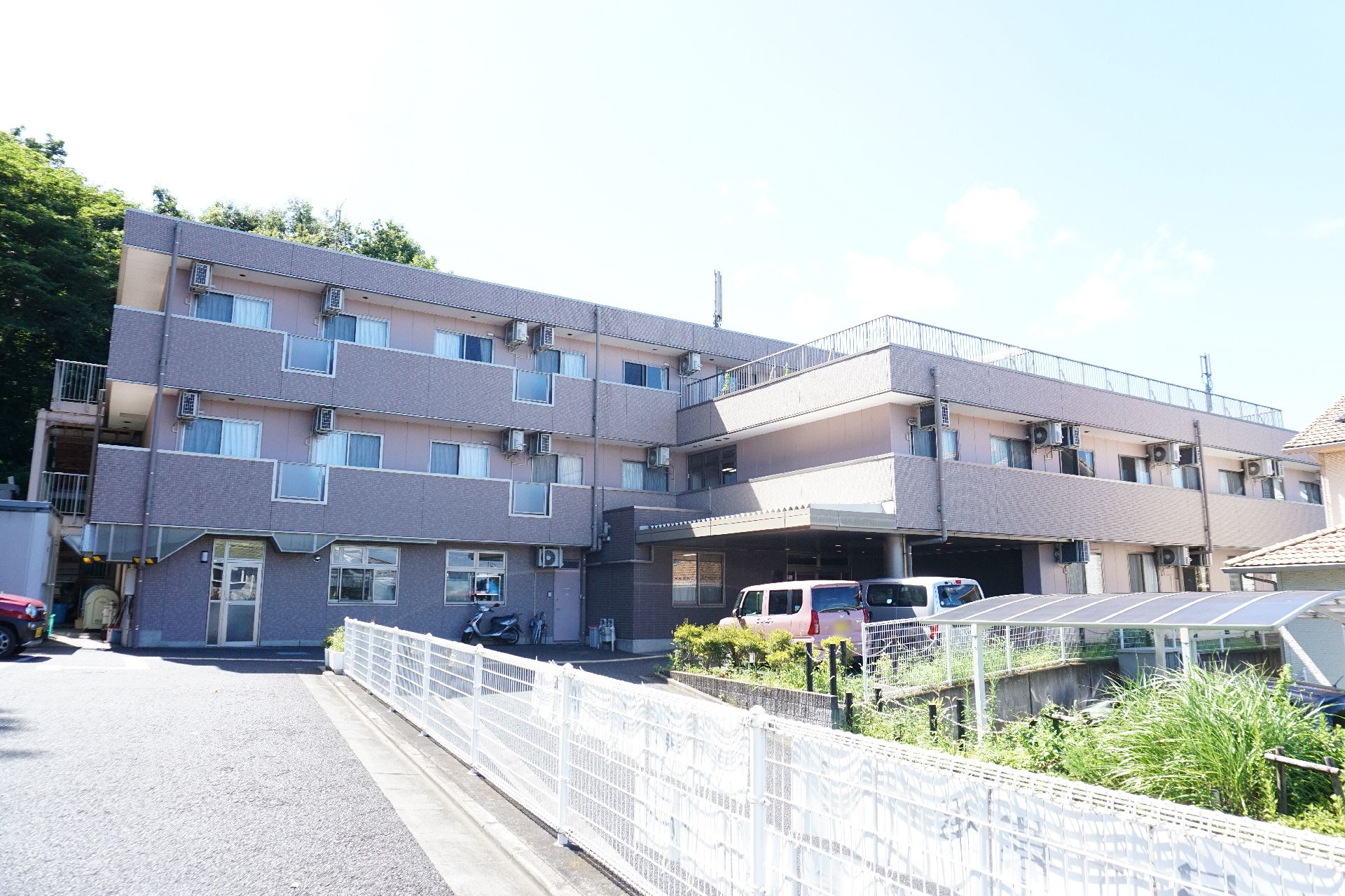 周囲に緑の自然があり、敷地に駐車場があるのがわかる施設の外観