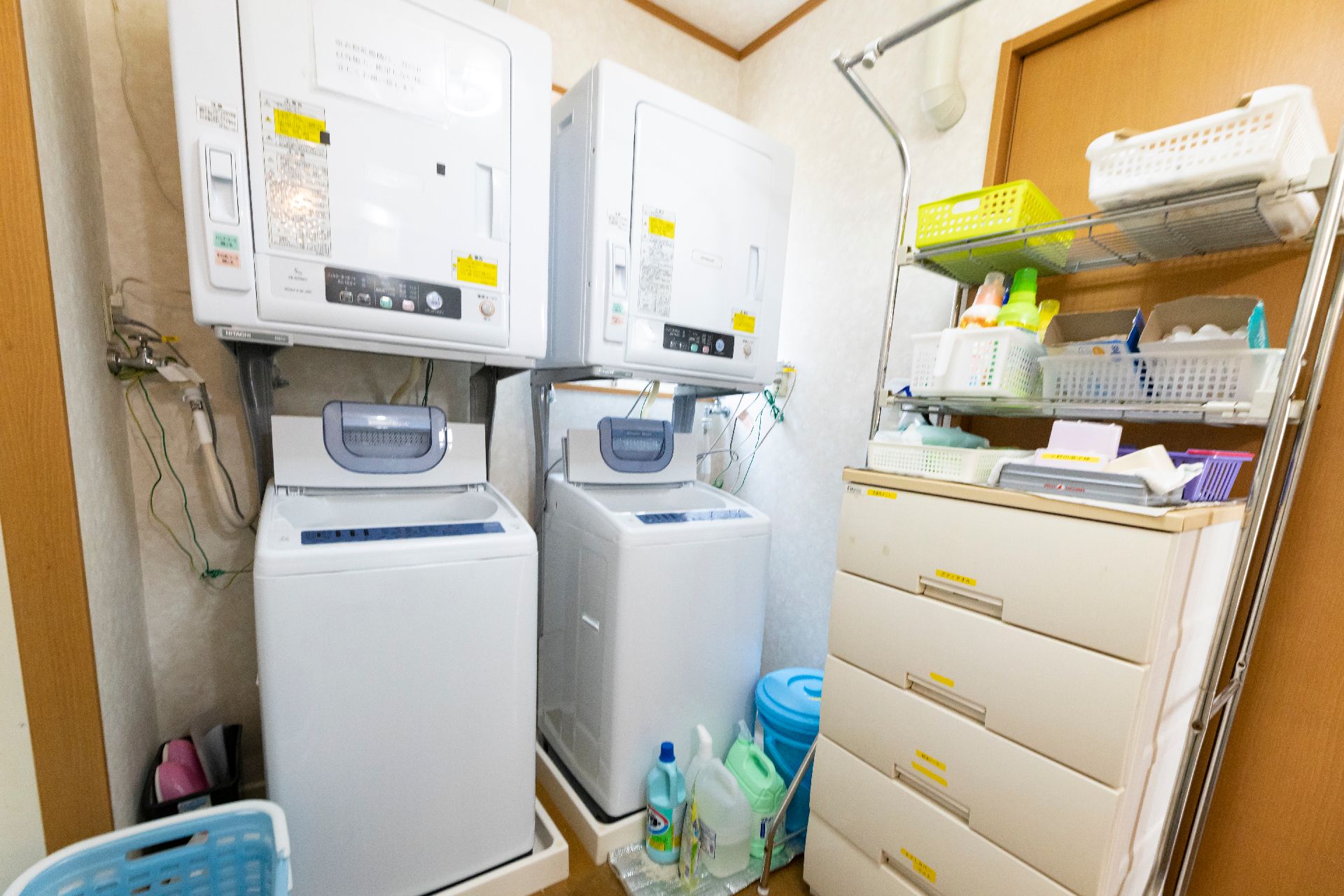 洗剤などが置かれ、洗濯機だけでなく乾燥機も設置されたランドリー