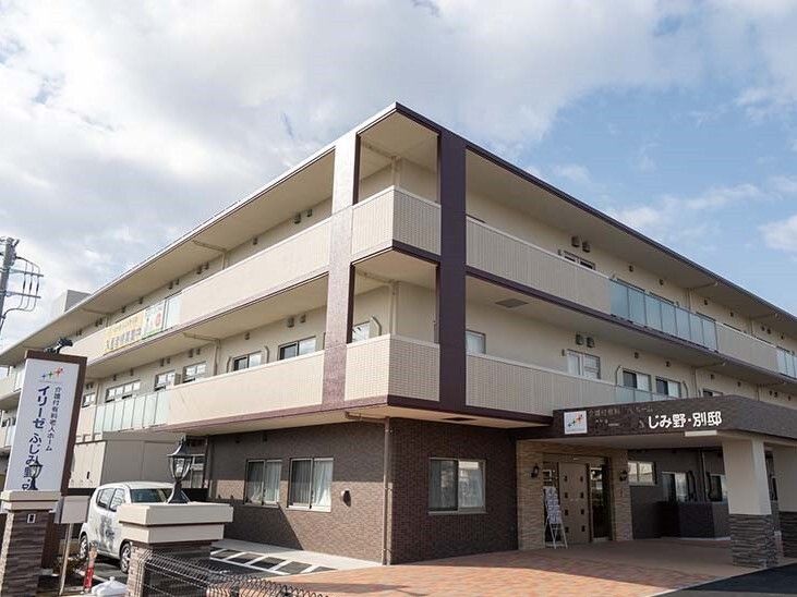 3階建ての建物。クリーム色と茶色の外壁