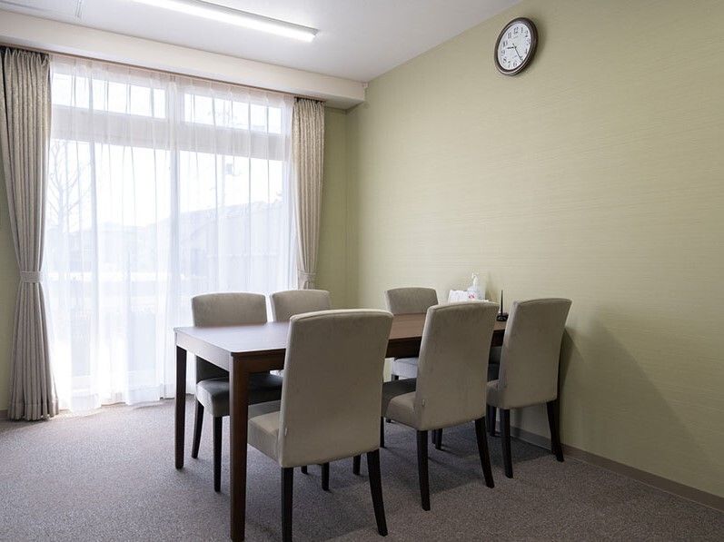 6人掛けのテーブルセットが置かれた部屋には大きな窓があり、レースカーテンとカーテンが付いている。
