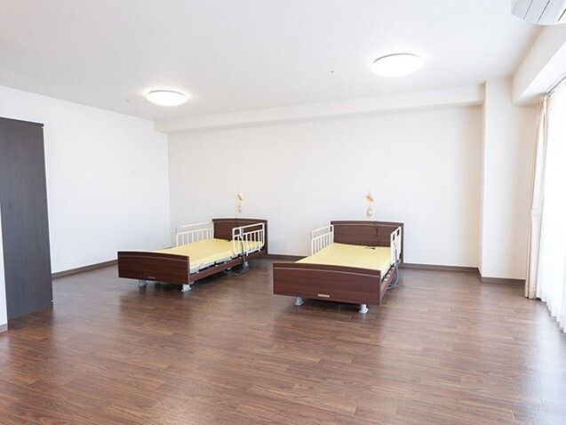 広いフローリングの部屋には介護用ベッドが二つ並べて置かれ、それぞれ緊急通報装置が設置されている。