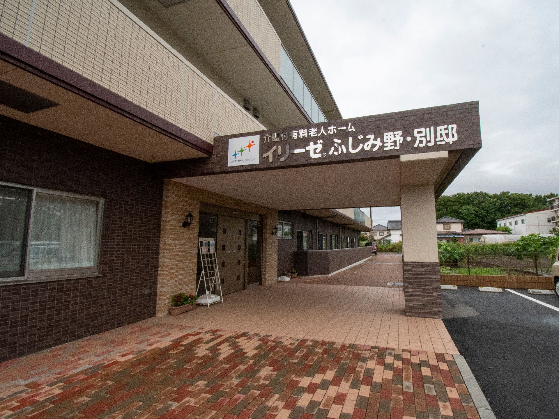 ロゴマークを表示した屋根付きの玄関前