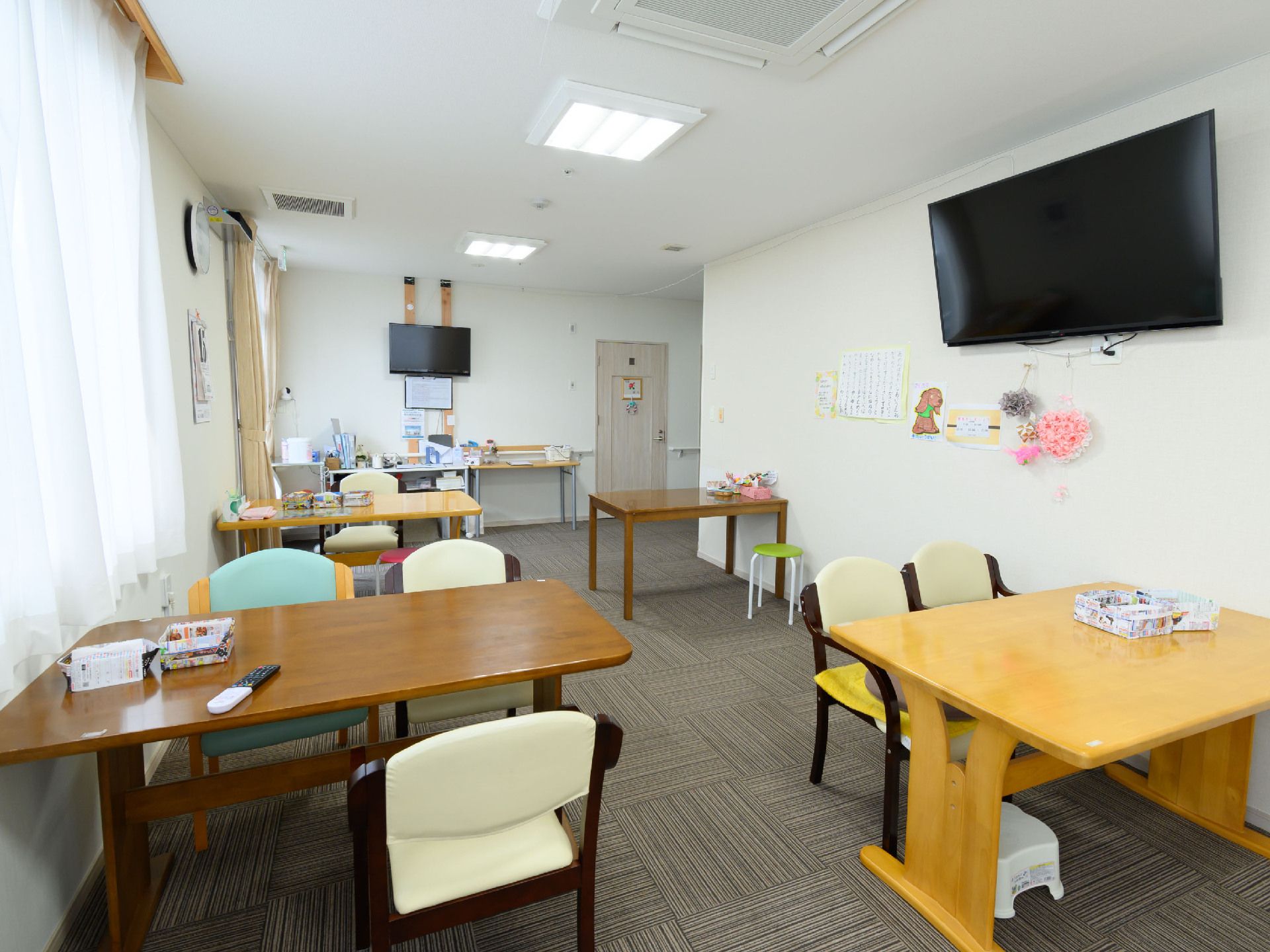 細長い白い壁の部屋に置かれた茶色の机と白い椅子
