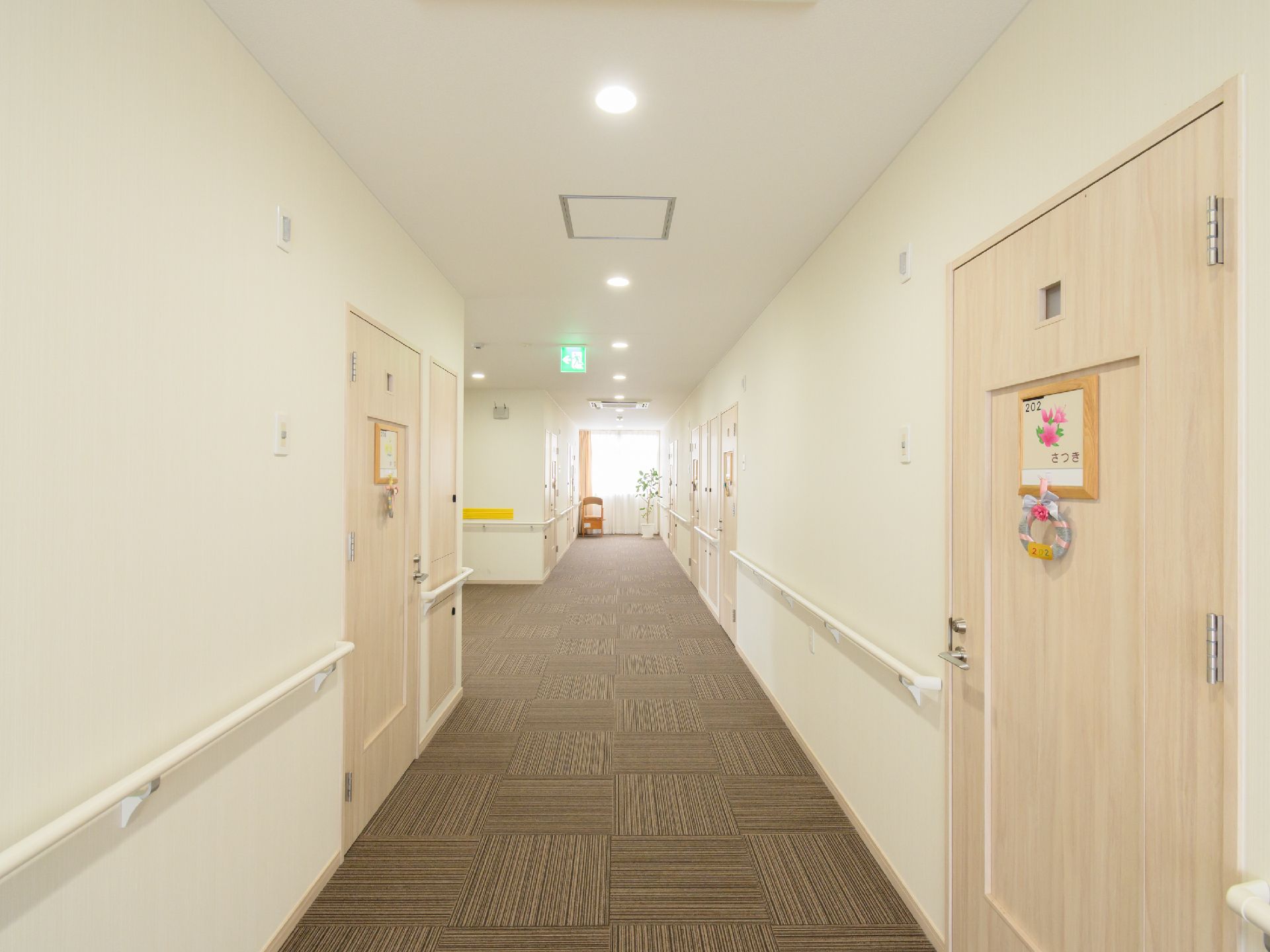 両側の白い壁に手すりが付いている直線の廊下