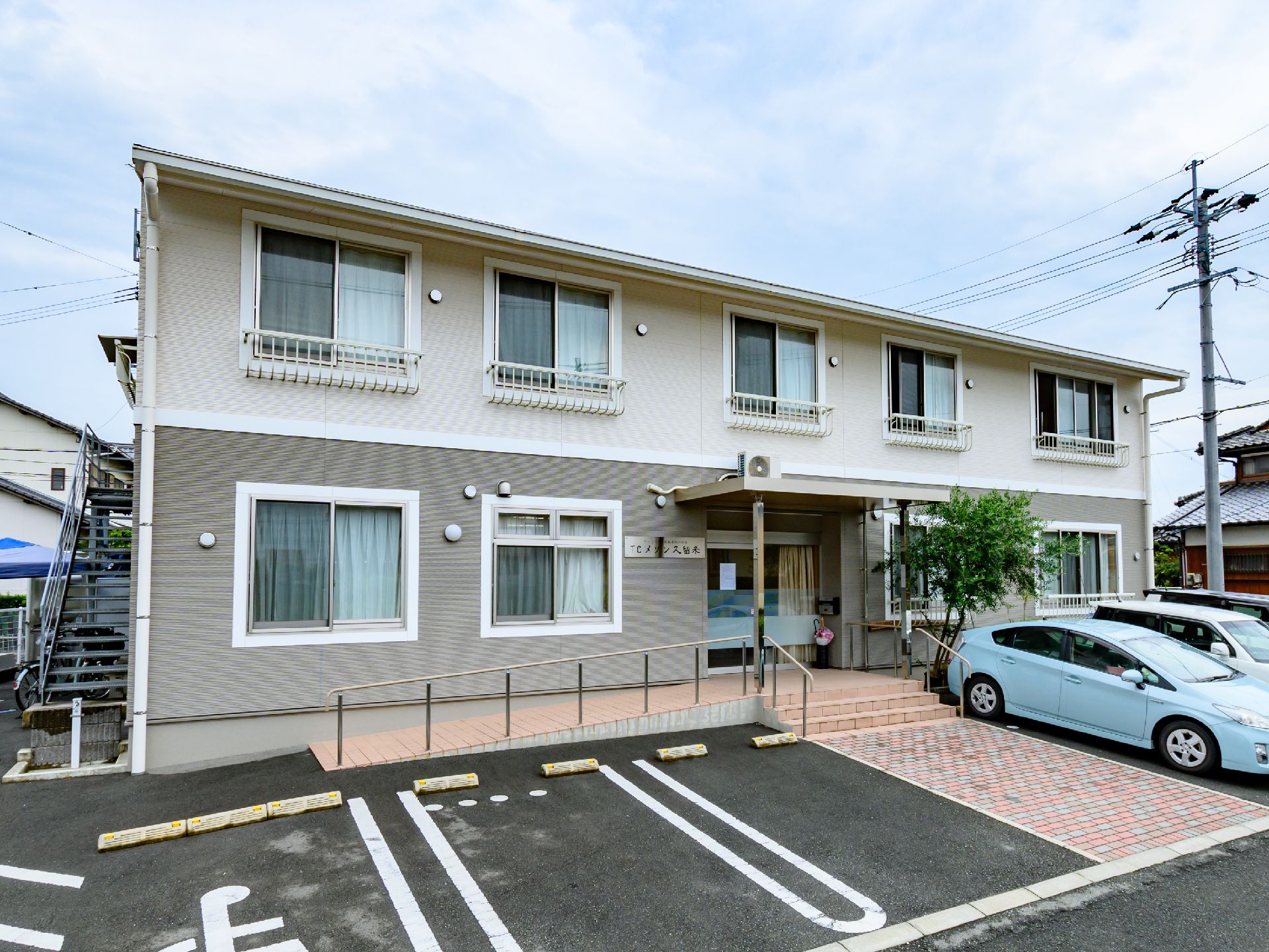 目の前に駐車場が設けられた白と灰色の外観の２階建ての建物