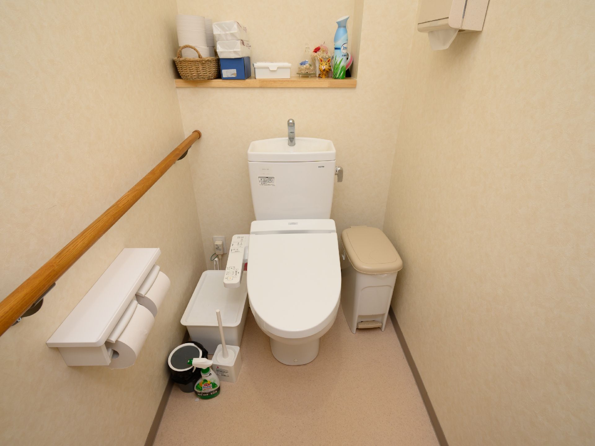 白い壁に木製の手すりが設置されたトイレ