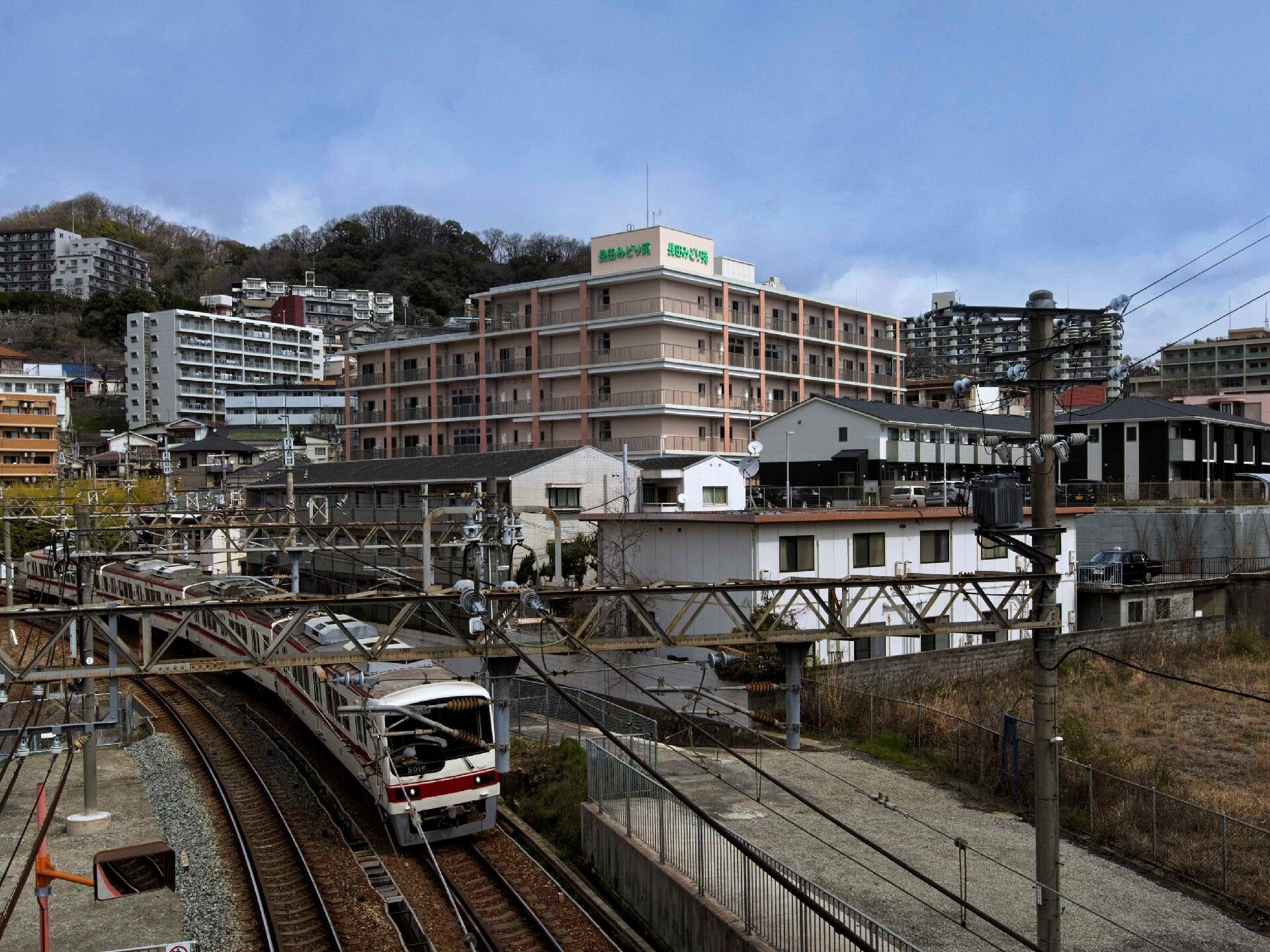 建物の周りには自然がたくさん残っているが、電車が通っていたり、背の高いマンションのような建物があったりと、ほどよく便利な環境がある。