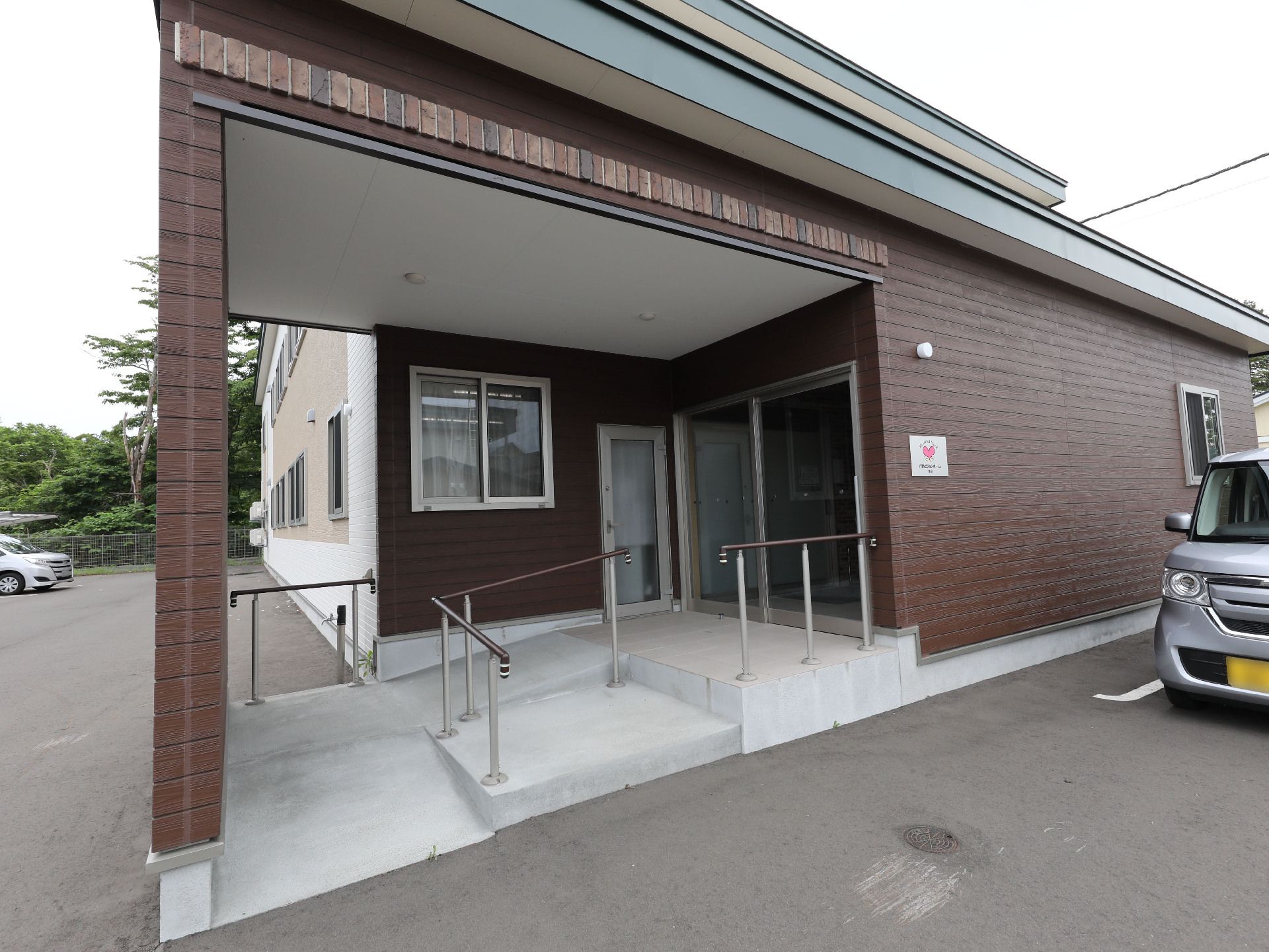 車が目の前に止まっている茶色の建物