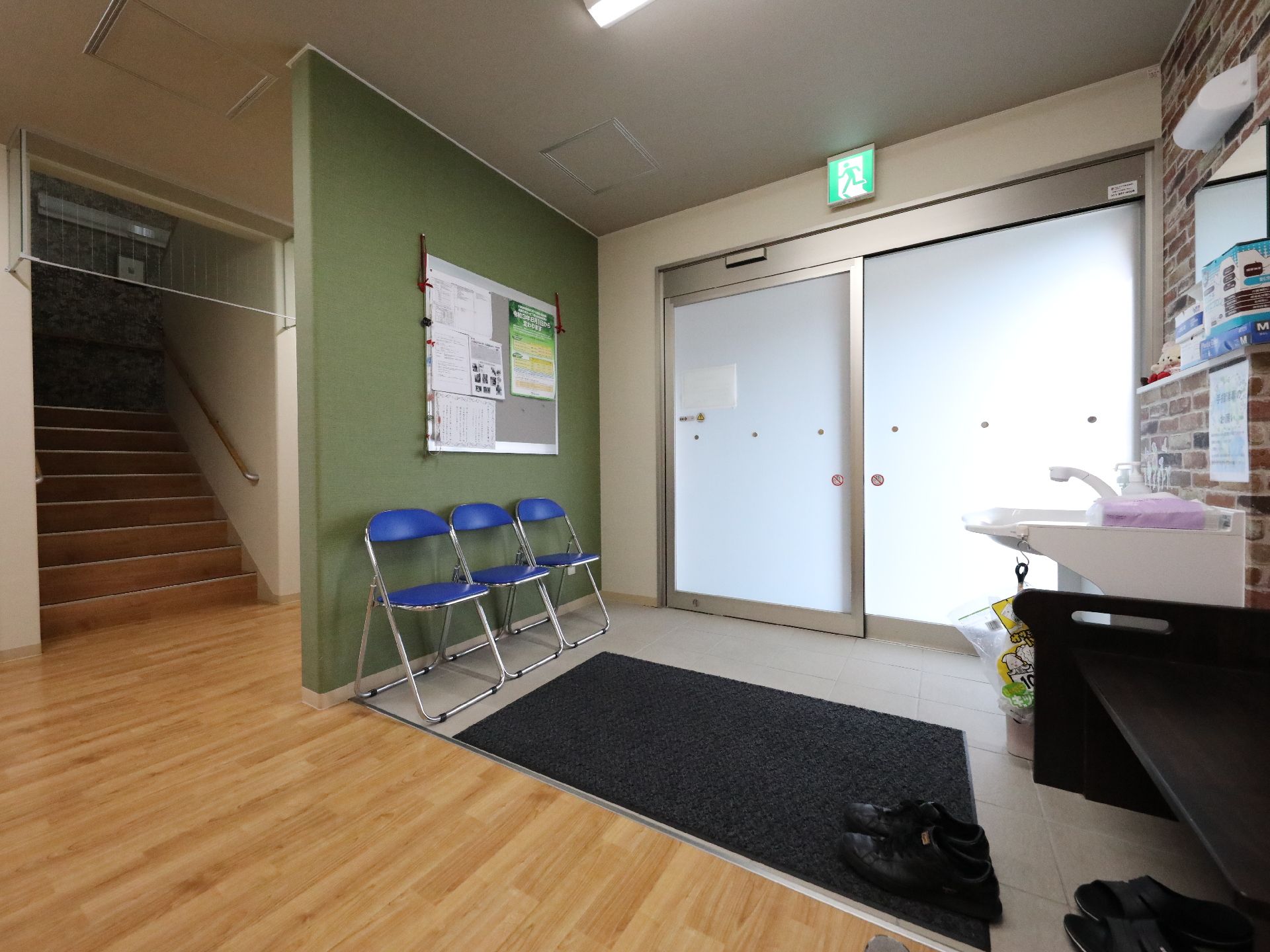 自動ドアの手前に３脚並んだ青いパイプ椅子
