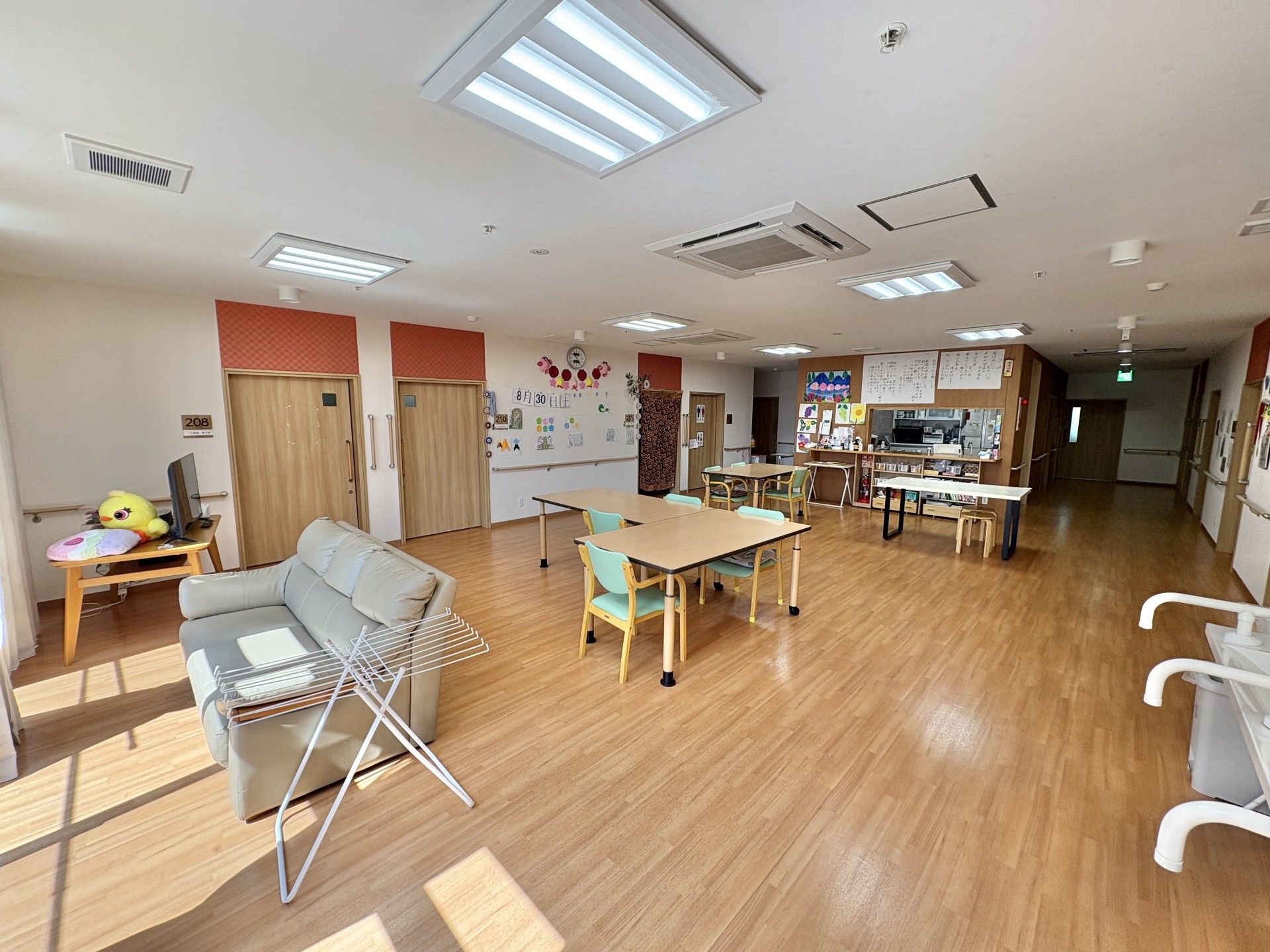 車椅子に乗って手を振る高齢女性と後ろで見守る女性ヘルパー