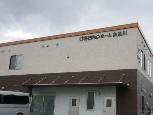 介護車両から降りた車椅子に乗った高齢の男女と介助をするヘルパー