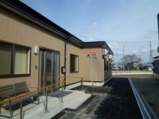 大きなドアが付いた玄関には手すり付きのスロープがあり、ベンチも置かれている。