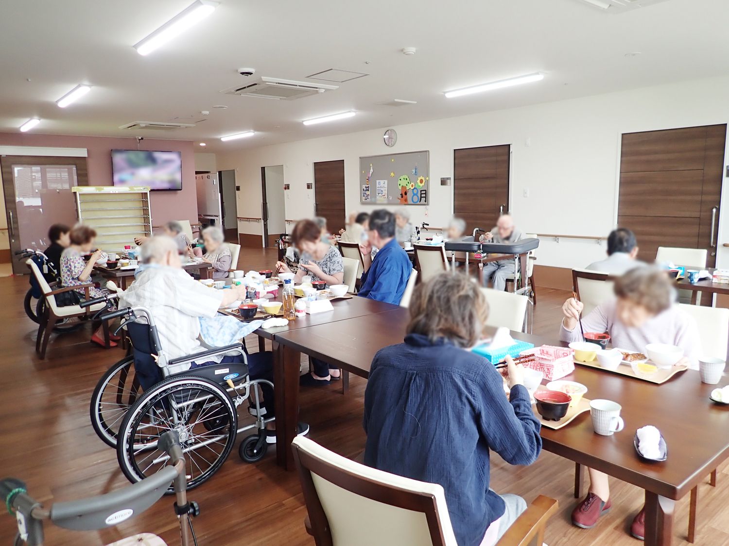 少人数用のダイニングテーブルが複数置かれたダイニング。観葉植物が置かれ、落ち着いた雰囲気。奥には車いす対応の洗面所がある。