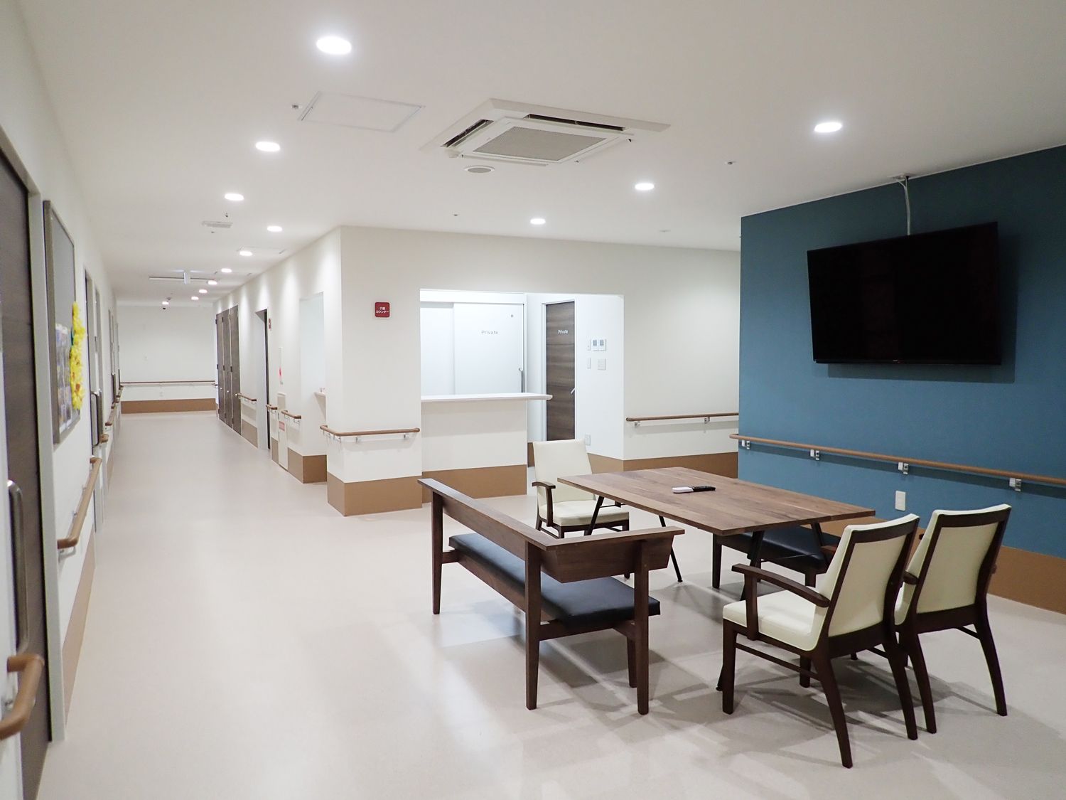 白い壁には木目調の手すりが付き、居室にはダークブラウンの大きなスライド式のドアが設置され、通行の妨げとなるものはない。