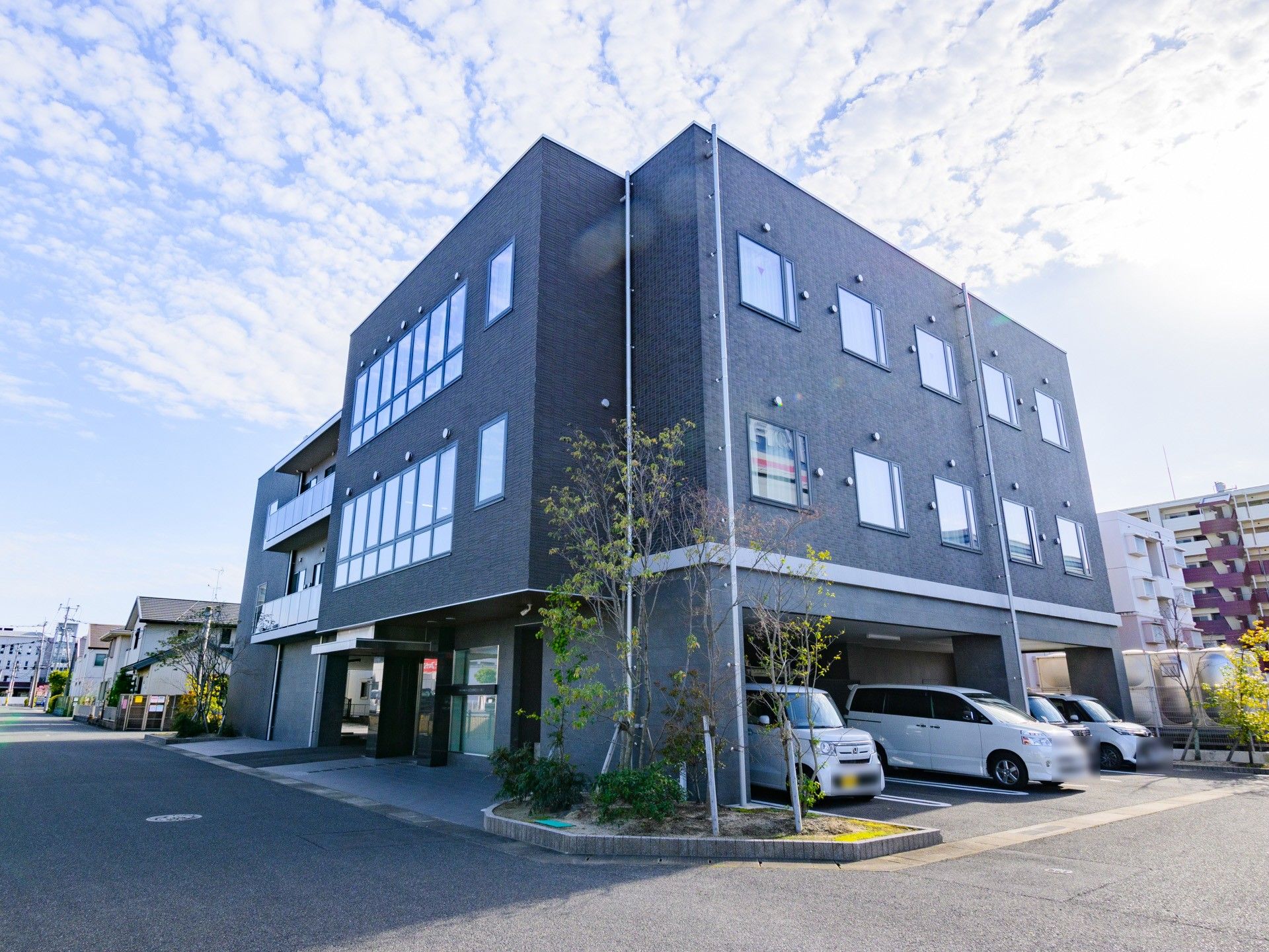 モダンな外観の3階建ての建物。グレーブラウンが基調となり、シックな雰囲気を醸し出す