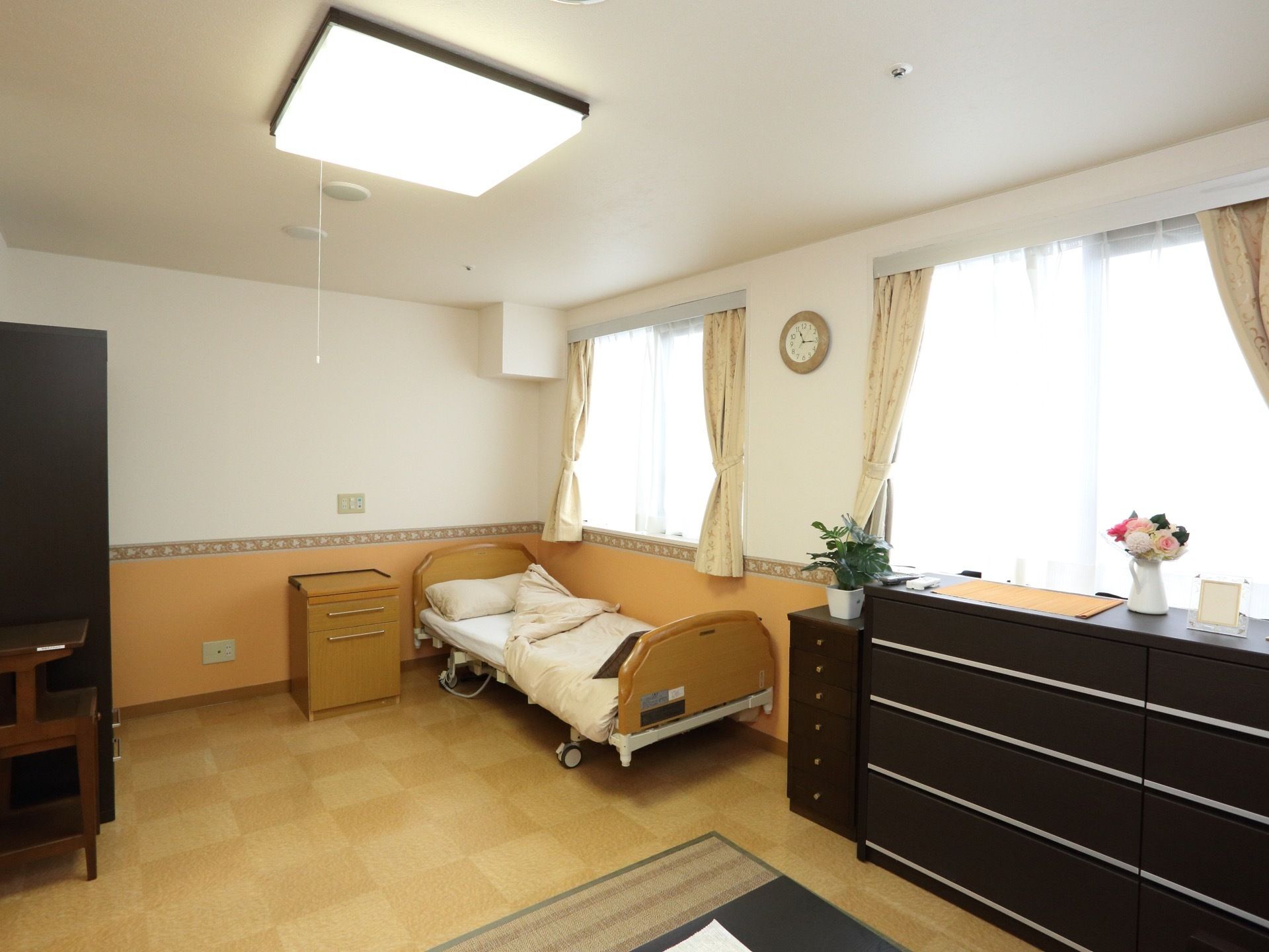 入居者様に割り当てられる居室。一部屋当たりの面積が広く作られている。壁の中央やや下を中心に白と黄土色に分かれている。