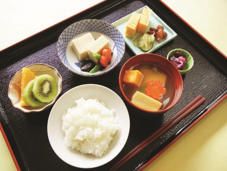 高野豆腐の煮物とたまご焼きや黒豆、ご飯と汁物とカットフルーツのデザート