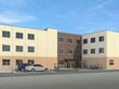 3色の外壁で、駐車スペースと駐輪スペースがある3階建て建築物