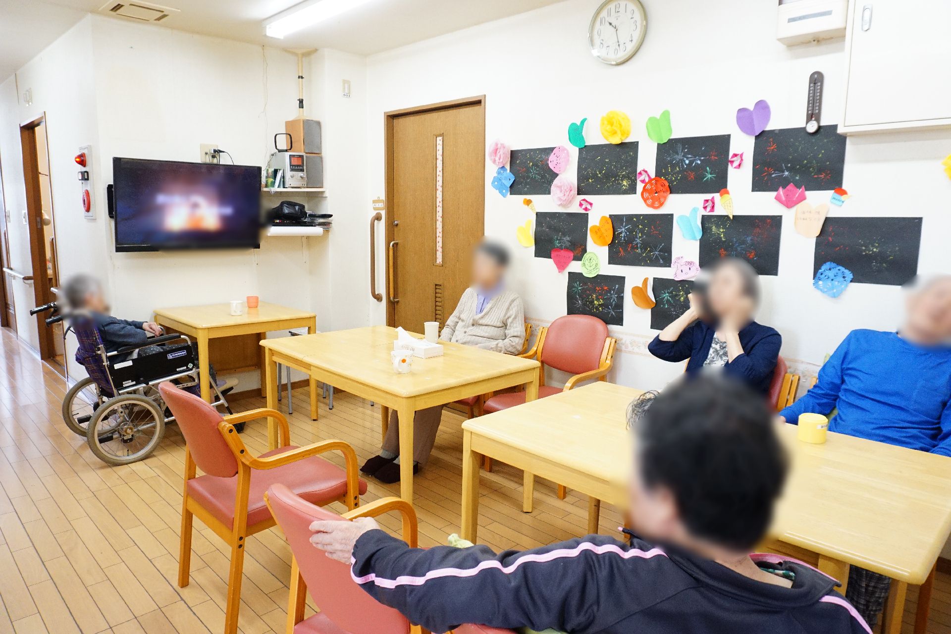 テーブルが多数置かれ、壁に展示物がたくさん飾られているリビング