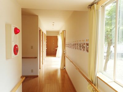 両手に手すりが設置された廊下はまっすぐで、左側に続く通路もあり、壁には防災設備や写真がたくさん掲載されたホーム新聞のようなものが飾られている。