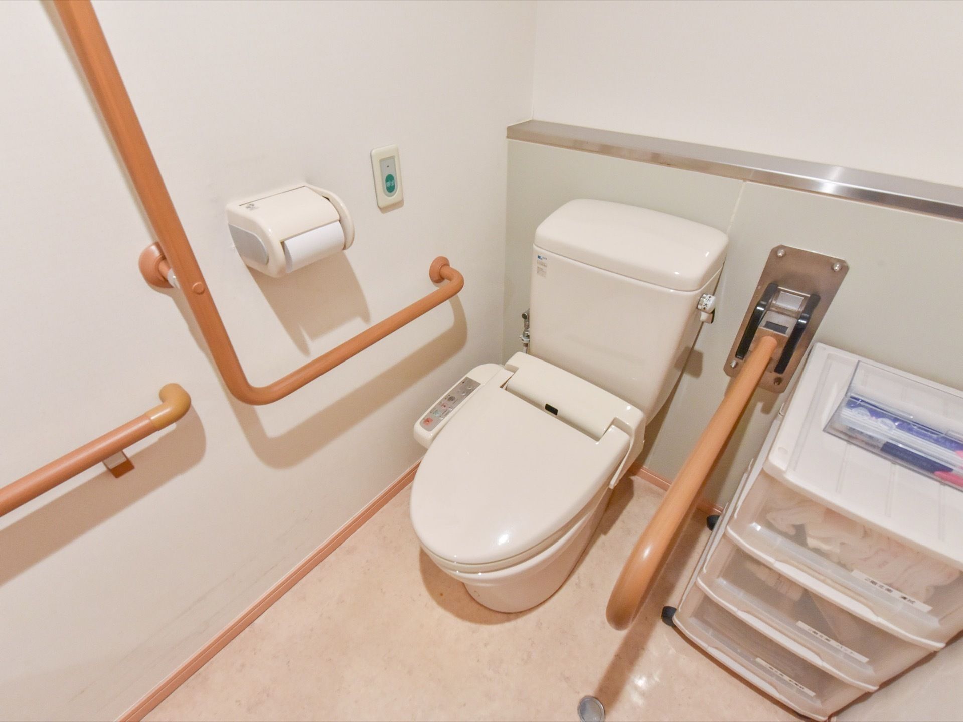 トイレにある便座の両サイドには手すりがあり、しっかりと固定されている。壁にはトイレットペーパーと、呼び出し用ブザーが付いている。