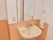 トイレの横に洗面台があり、正面には縦長の鏡がある。鏡のそばにはコンセントがあり、横にはタオルが掛けられている。