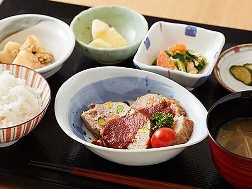 白いご飯に味噌汁、ミートローフや肉じゃが、あえ物などが並べられたトレーには箸も置かれている。