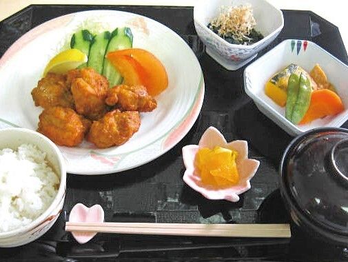 白いご飯に味噌汁、漬物に煮物、おひたし、そしてメインのから揚げにはトマトやキュウリ、レモンが添えられている。