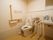 白い部屋の一角に設けられた手すりに囲まれたトイレと足元が空いている洗面台