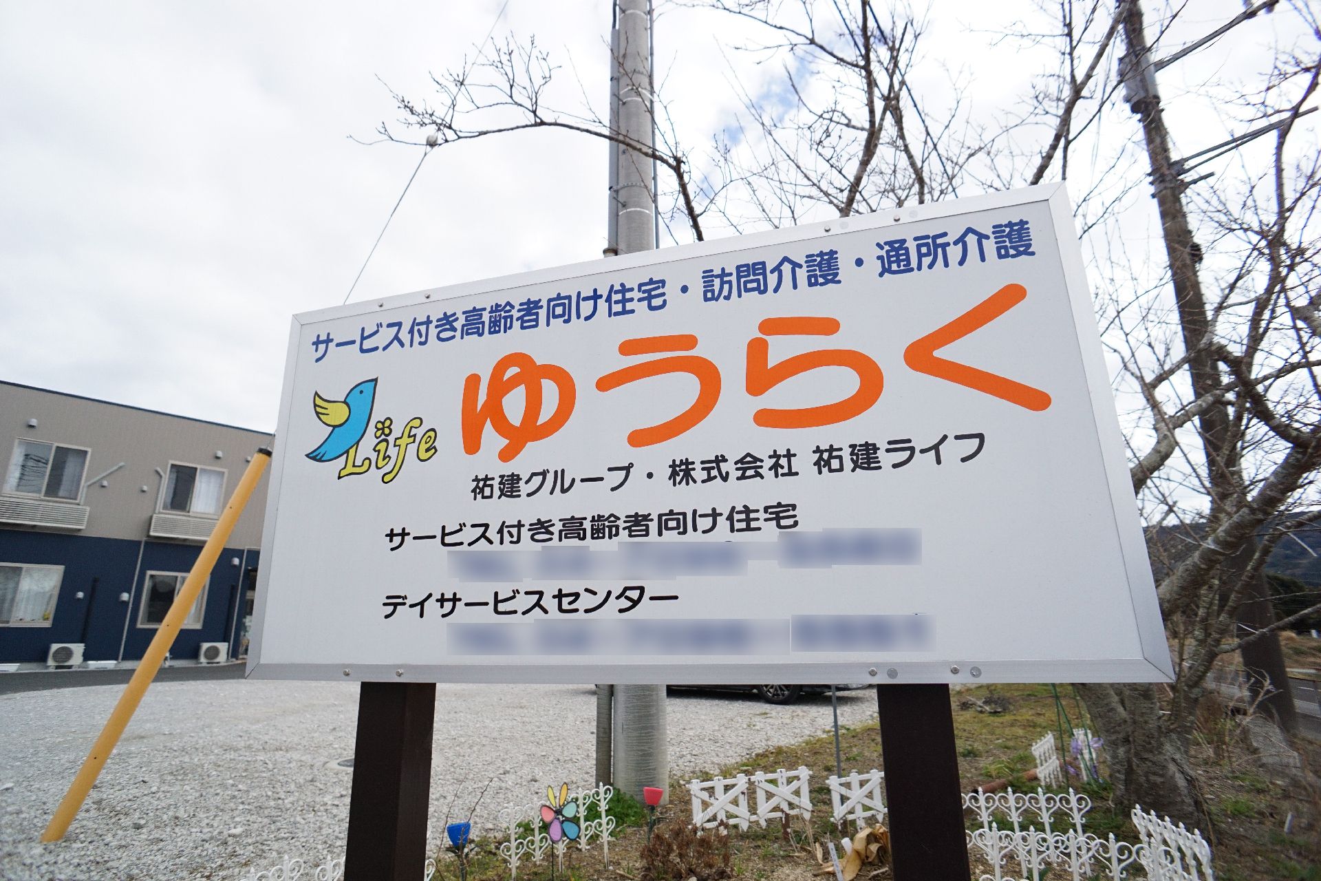 ブルーのユニフォームを着た男性スタッフが高齢女性の横に立ち、二人とも楽しそうに体操をしている。