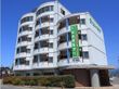 ６階建ての建物は白を基調としていて「入居者募集」と書かれた垂れ幕がかかっている。周りには緑も多い。
