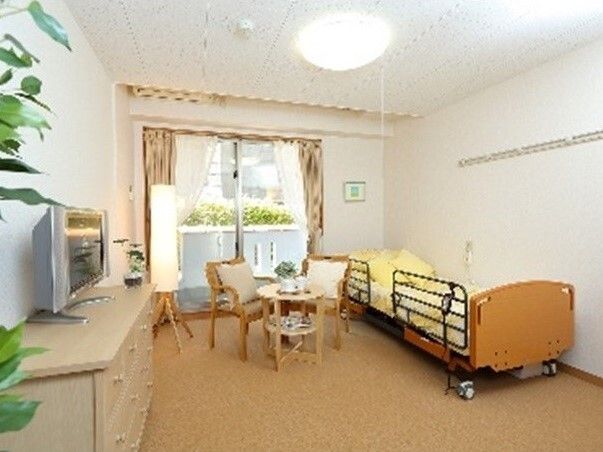 ベッドサイドには緊急通報装置があり、大きな窓が付いた一人用の部屋。テレビやタンス、テーブルセットもある。