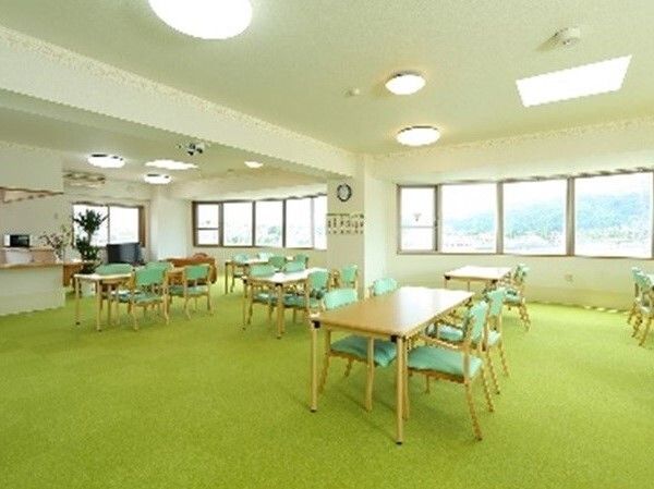 たくさんのダイニングテーブルが置かれた明るい雰囲気の共有スペース。観葉植物も飾られている。