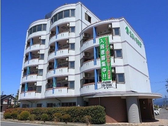 「入居者募集」と書かれた垂れ幕がかかった白を基調とした建物は重厚感があり、奥には駐車場もある。