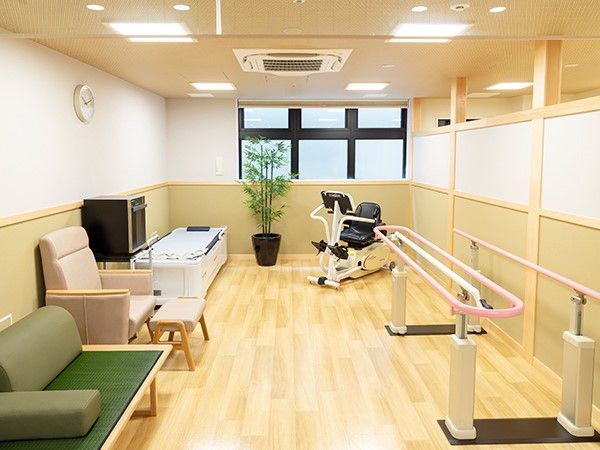 リハビリマシーン、歩行訓練用平行棒、いすなどが置かれている部屋