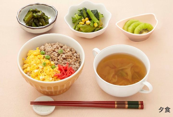 たまごとそぼろ煮の二色丼や、野菜の小鉢とスープ、キウイフルーツのデザートが付いたメニュー
