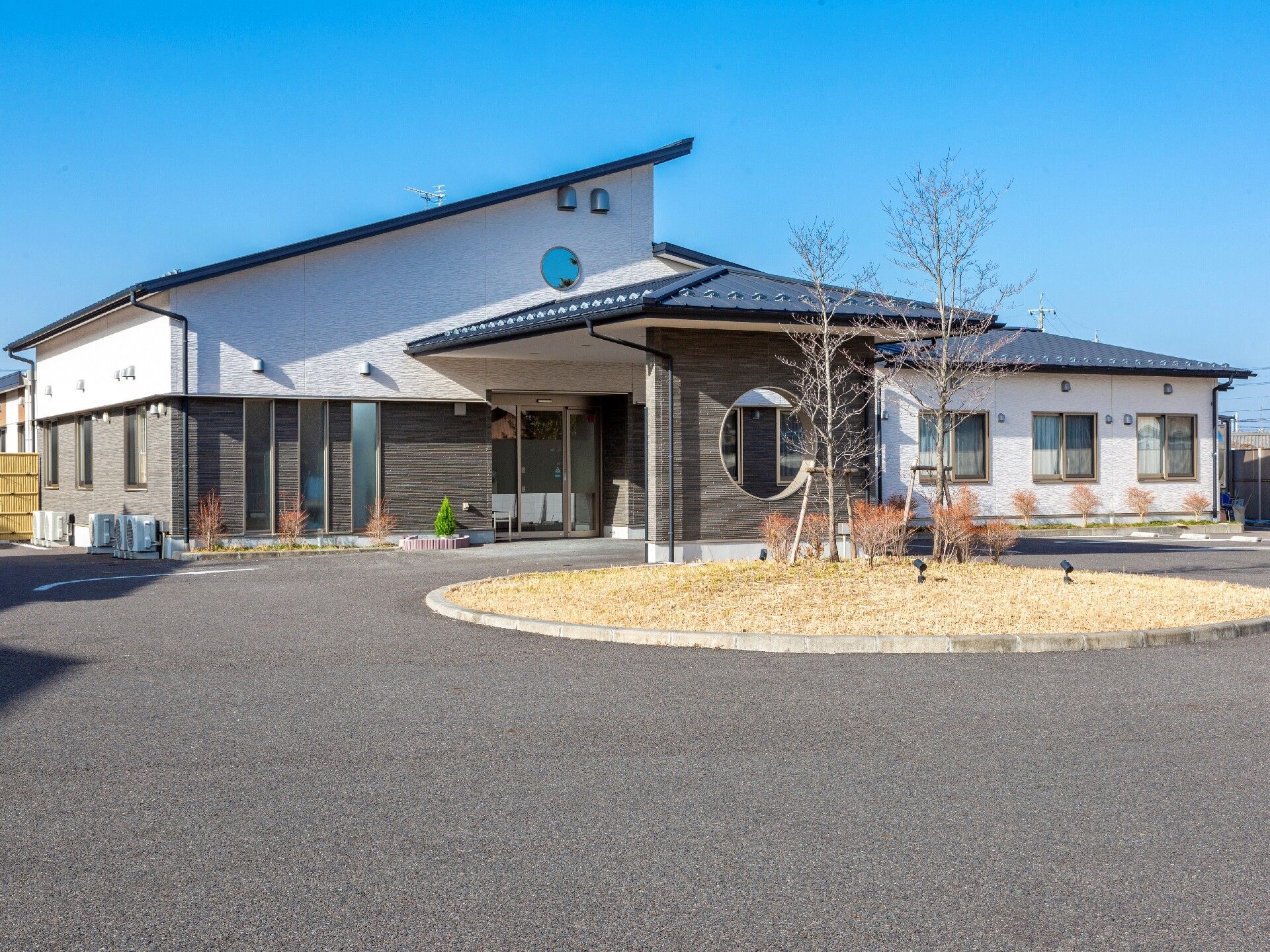 周りにグリーンを配置したツートーンカラーの建物