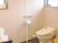 窓が二つ付いた広いトイレ。小さなゴミ箱や黒い棚があり、トイレの横には天井からフロアまで続く手すりが設置されている。