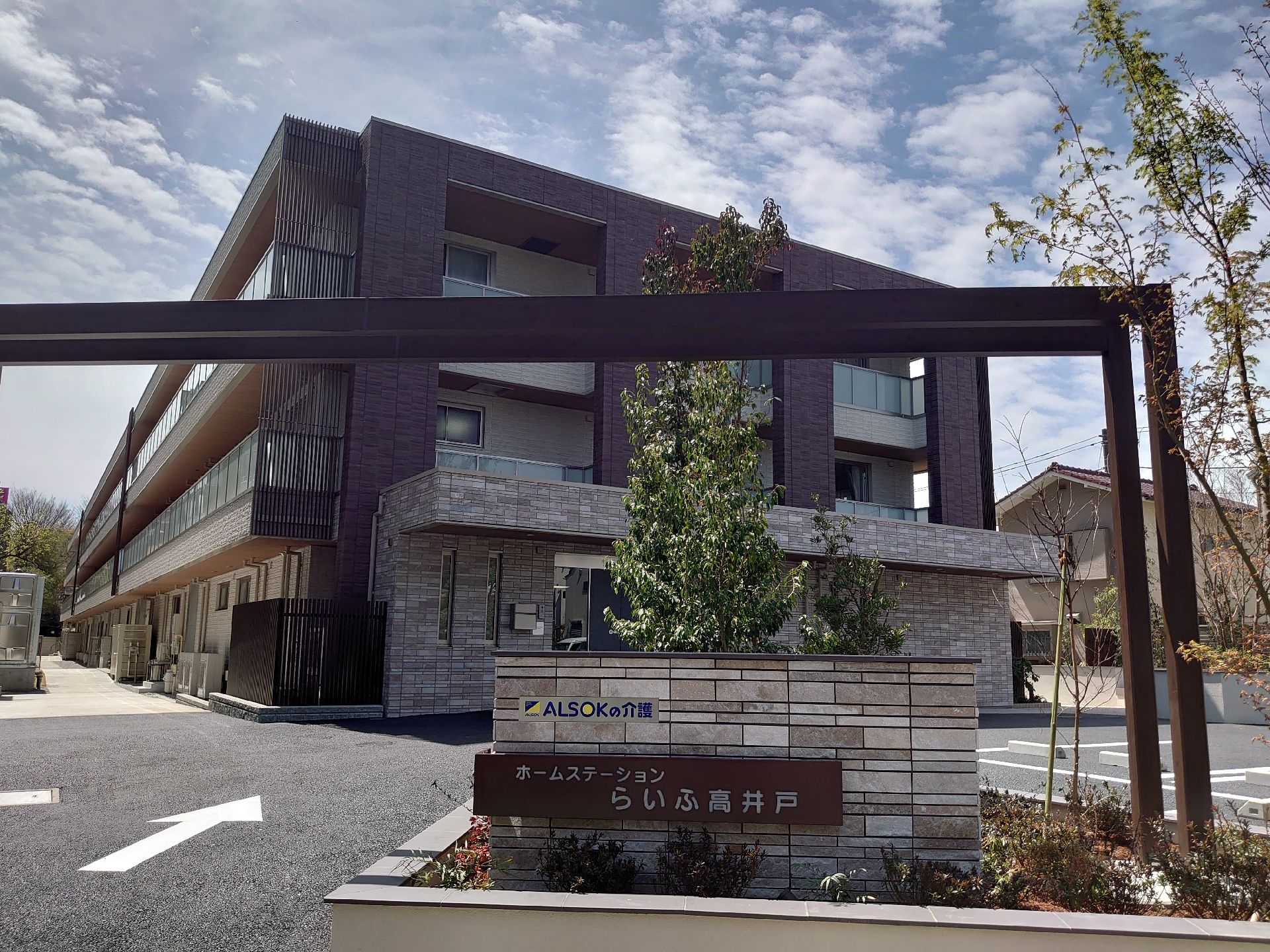 道路から少し入ったところに建っている3階建ての建物はブラウン系で統一され、落ち着いた雰囲気。草木もたくさん植えられている。