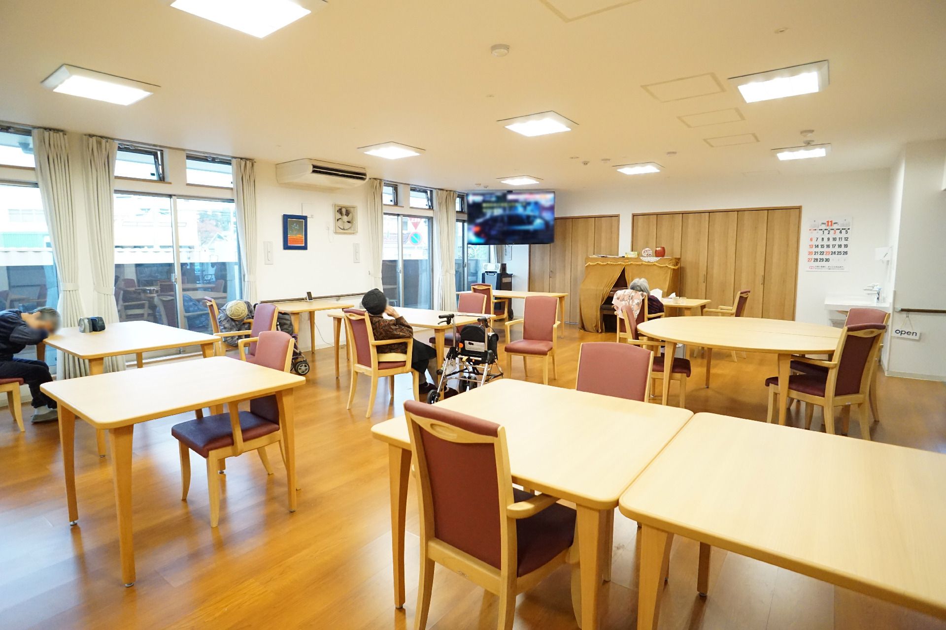 カーディガンを着た車いすの高齢女性とエプロンを付けた女性スタッフが笑顔で話している。