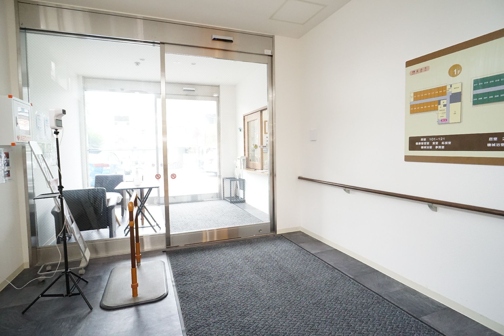 高齢女性の肩にタオルをかけながら笑いかけている紺のポロシャツを着た女性スタッフ。