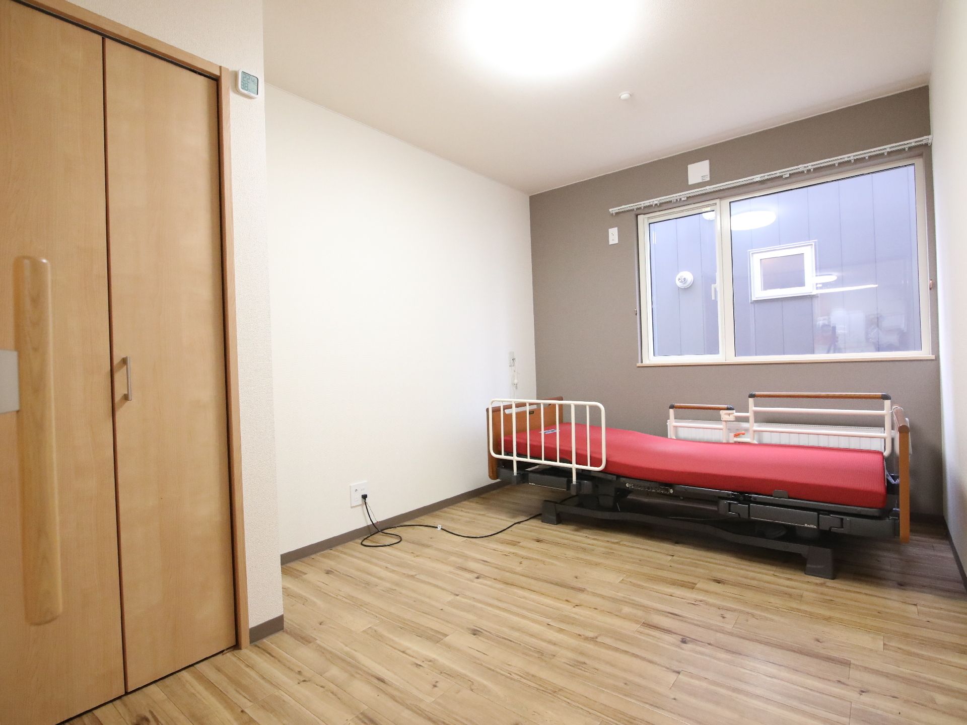 こちらを向いて笑顔になる車いすの高齢女性と介護施設の女性スタッフの様子