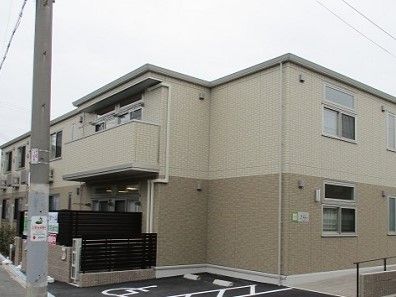 入り口にスロープがあり、茶色とベージュの外壁の2階建て建グループホーム
