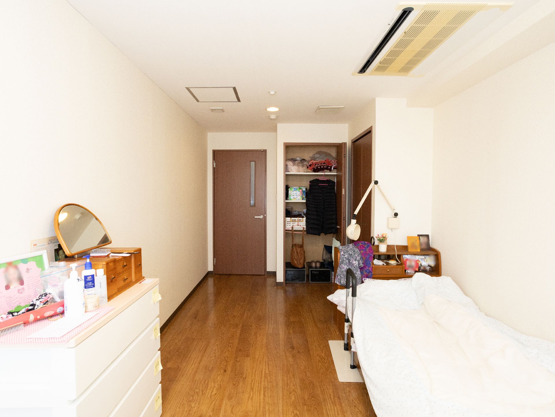 介護ベッド、タンスが置かれ、収納に荷物が保管されている居室